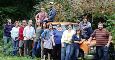 Group of home gardeners lined up along an orange truck.