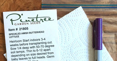 A lettuce seed packet, purple sharpie, and napkin for germinating seeds, laid out on a table.