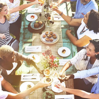 Large group of people eating at a colorful outdoor table.