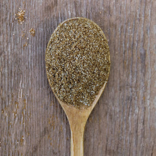 Light brown celery salt on a rustic wooden spoon.