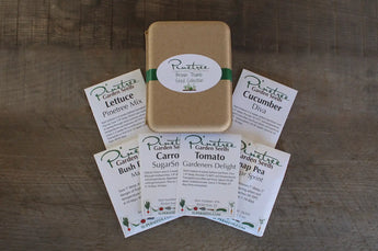 Collection of seed packets and a tan storage tin arranged on a surface.