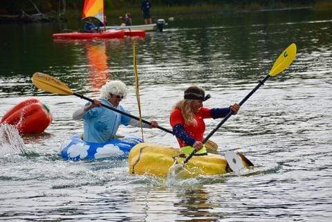 Group of people racing on river in giant floating pumpkins.