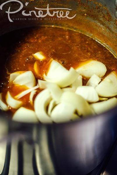 close up of cut onions added to the sauce in a pot