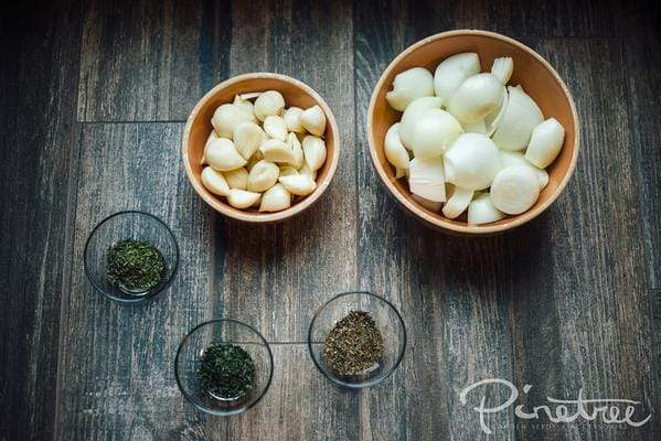 5 bowls with cut onion, garlic, and spices on a counter