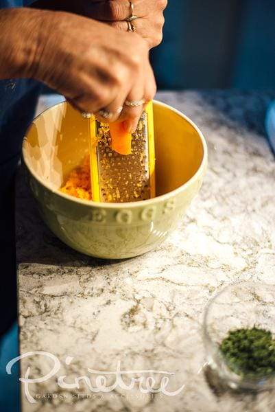 hands grating carrot into a bowl on a kitchen  countertop