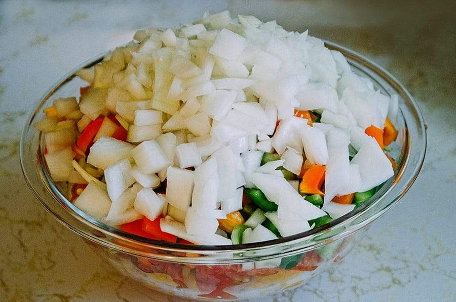 Garden fresh salsa with onions, peppers, and tomatoes, in a glass bowl.