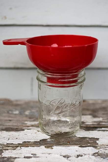 Bright red canning funnel set up in a mason jar.