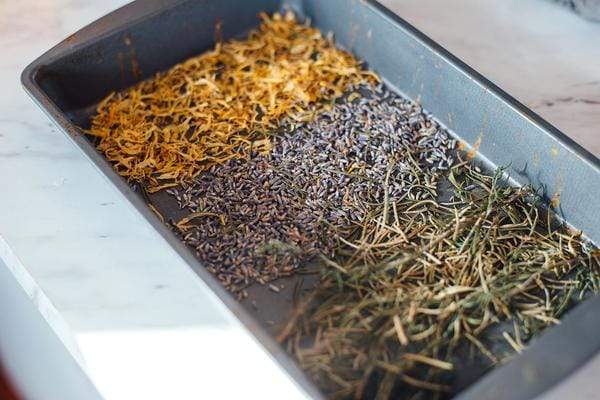 Garden herbs being dried in a baking pan.