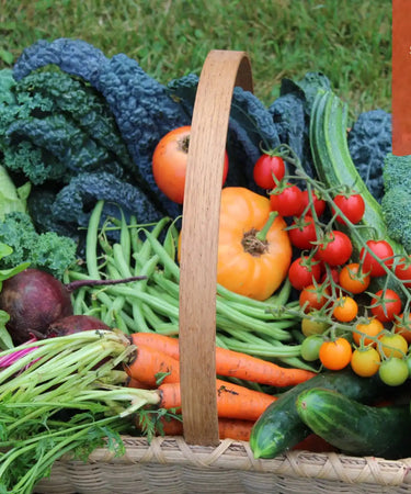 Wooden basket filled with fresh colorful vegetables and produce.